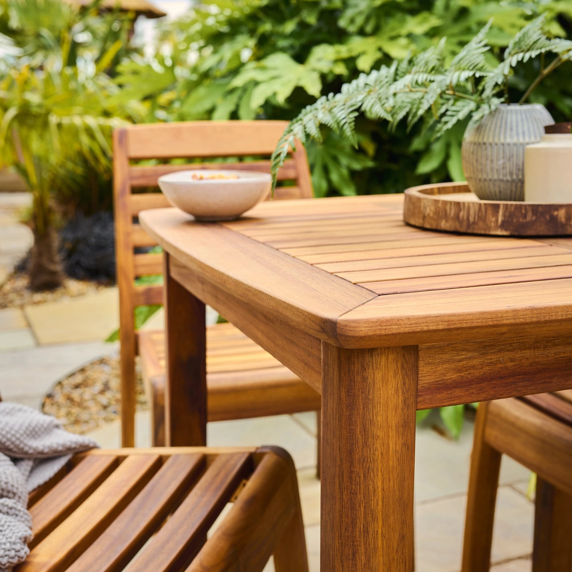 Wooden outdoor dining table and chairs with a garden background