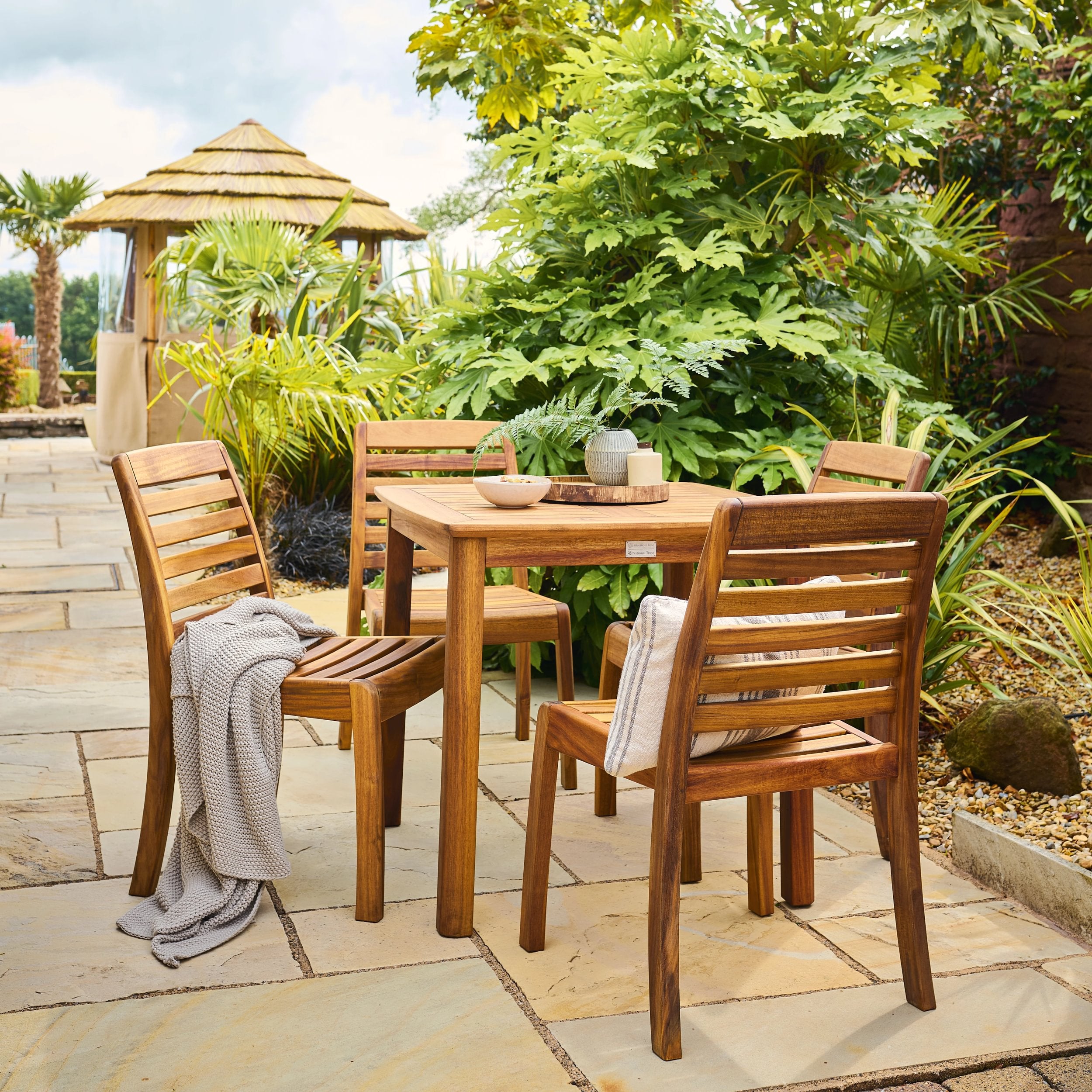 Wooden outdoor dining set with table and chairs in a garden setting