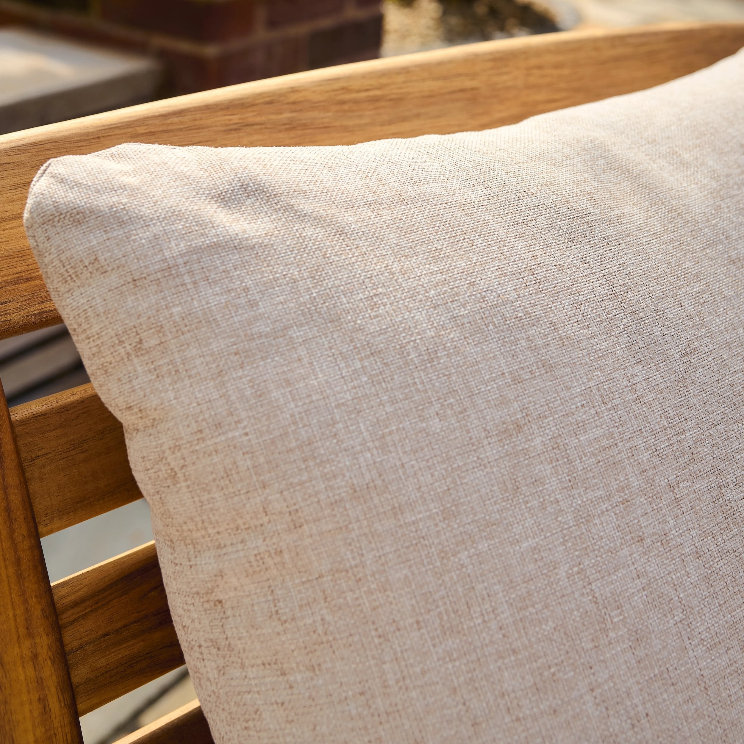 Beige cushion on a wooden chair with a blurred background