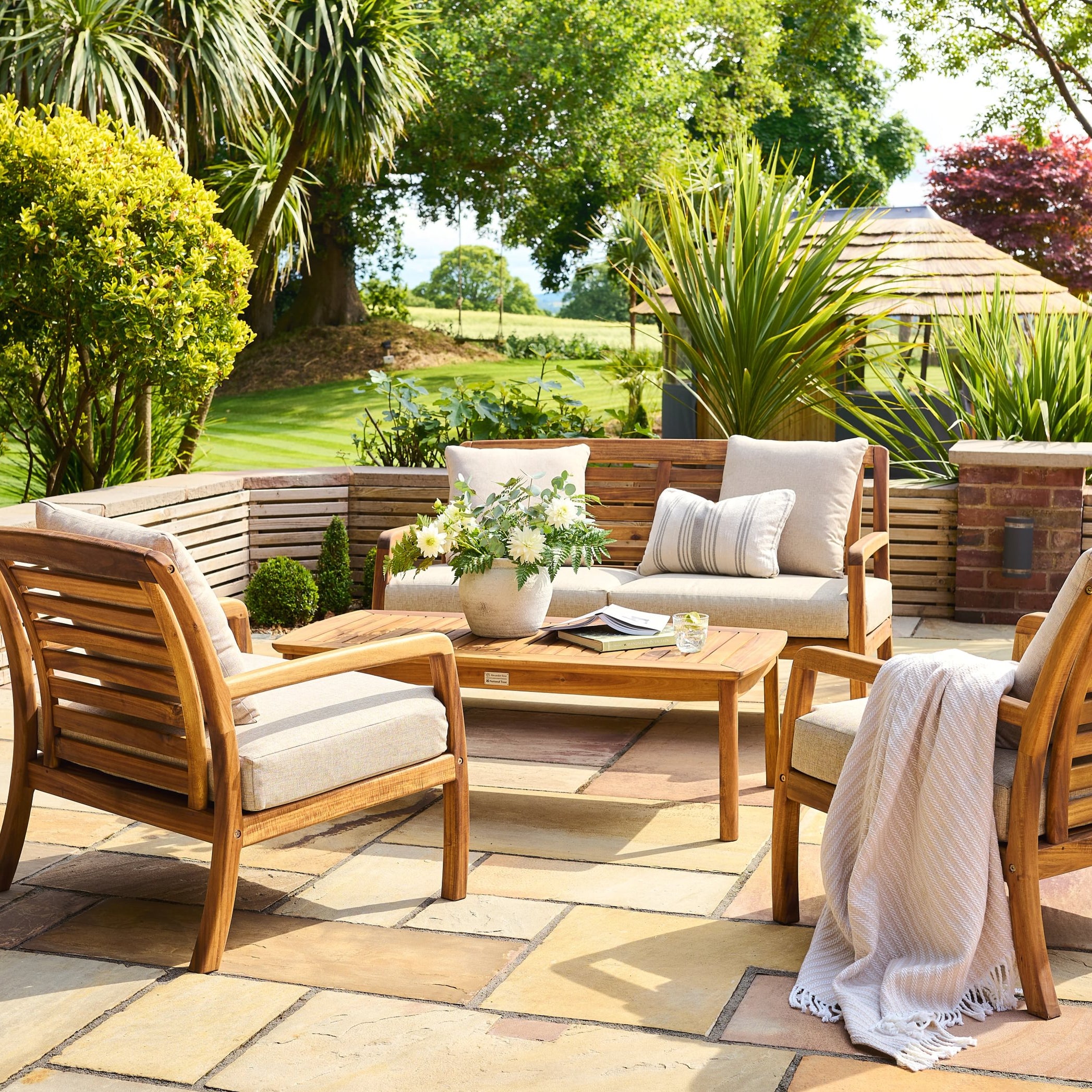 Outdoor patio set with wooden chairs and table in a garden setting