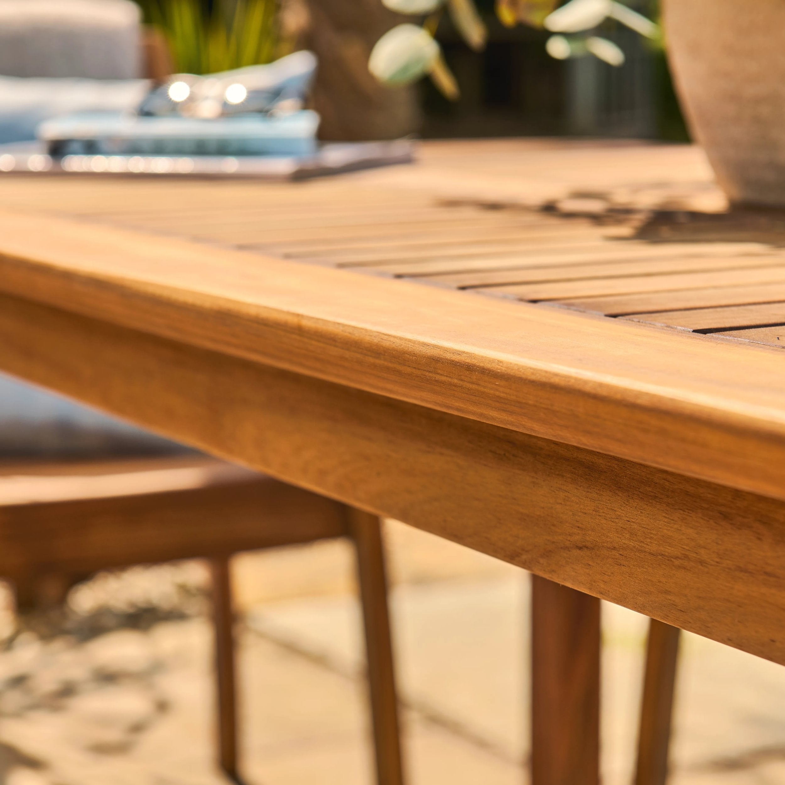 Close-up of a wooden table with a blurred outdoor setting in the background