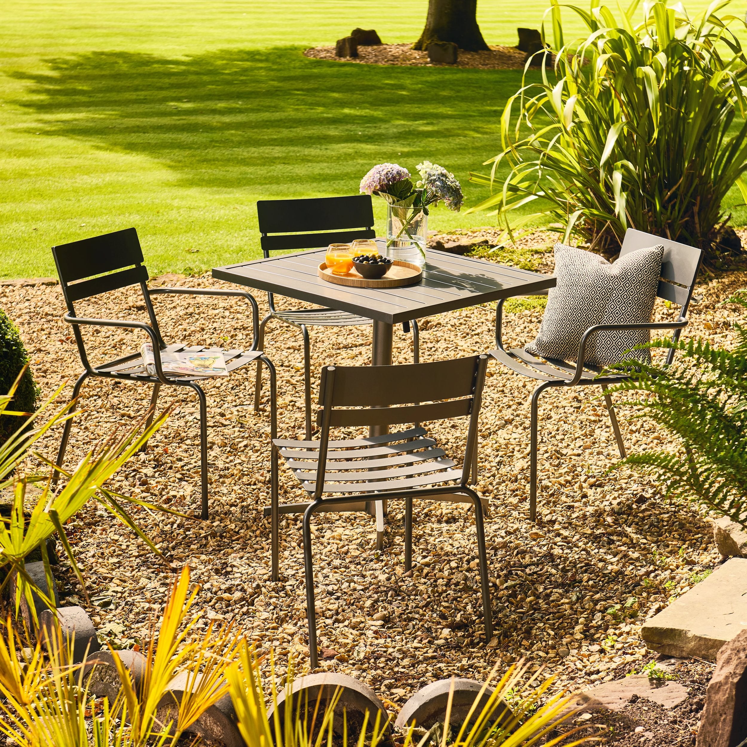 Outdoor patio set with table and chairs in a garden setting