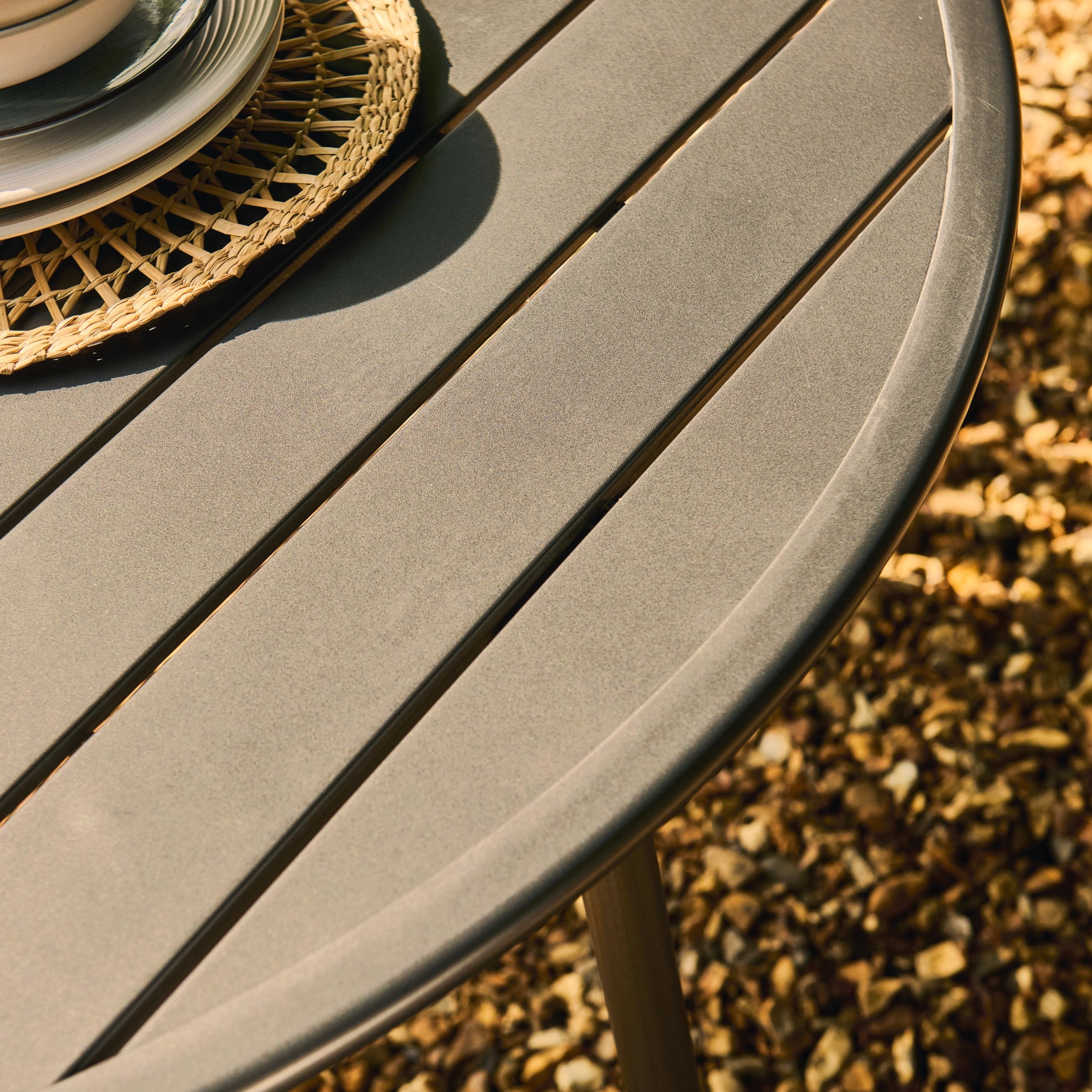 Round outdoor table with a textured surface on a gravelly ground