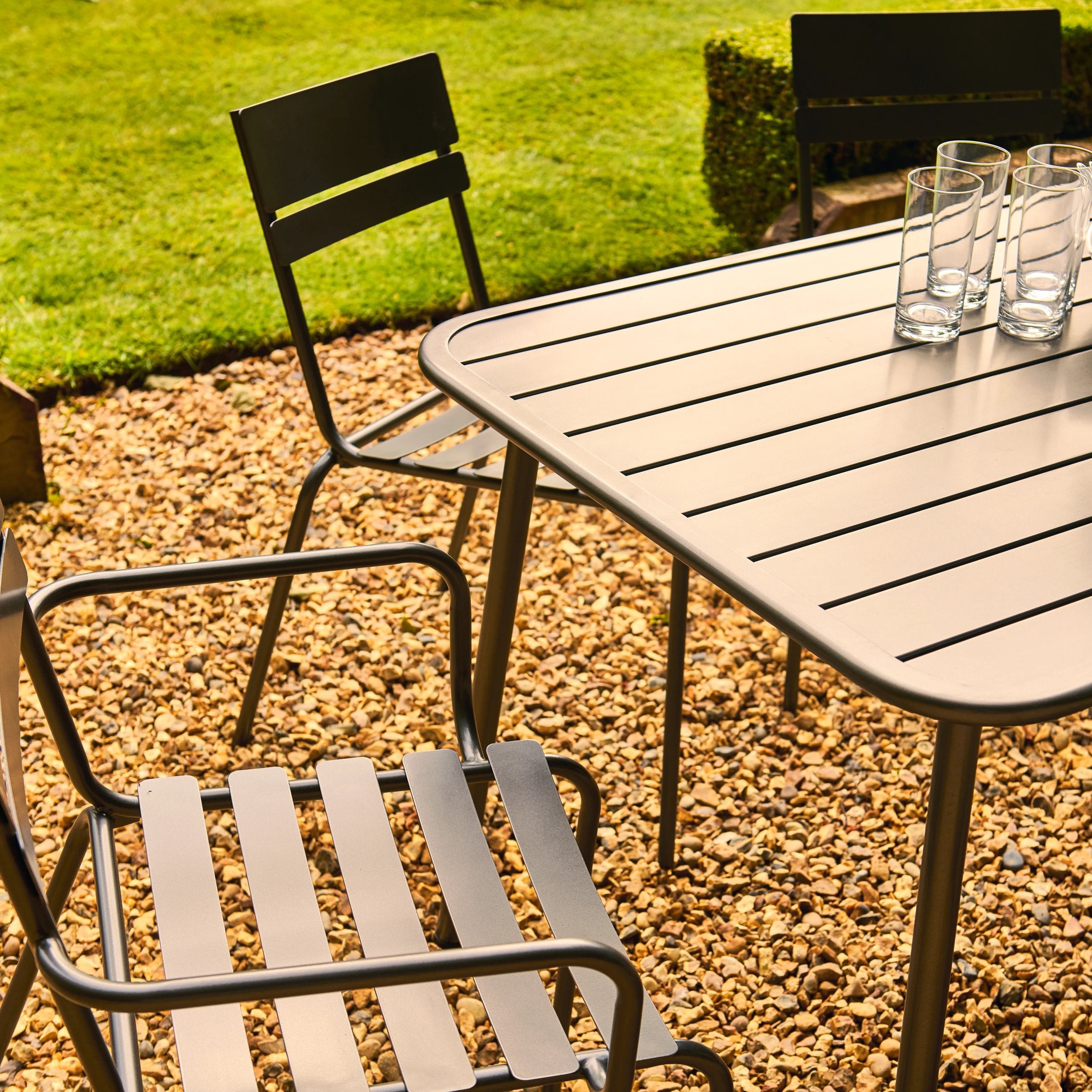 Garden table and chairs with glasses on a gravel patio