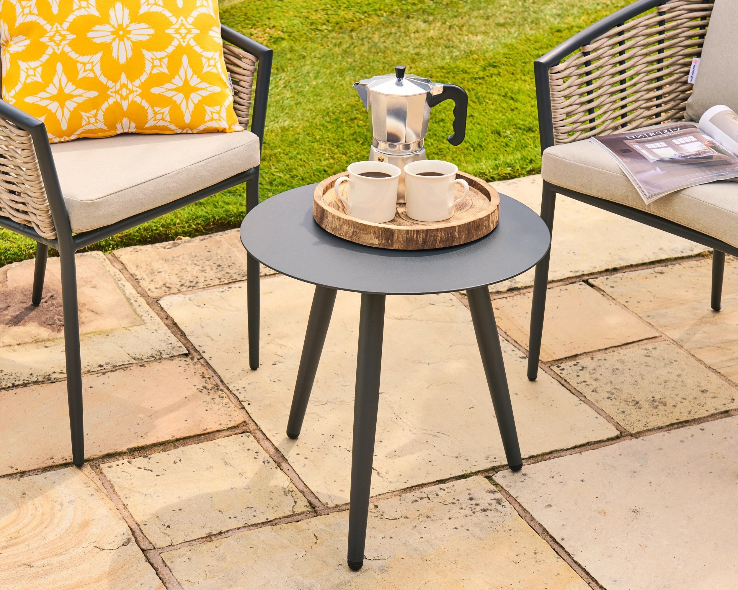 Outdoor patio setting with a small round table, chairs, and coffee