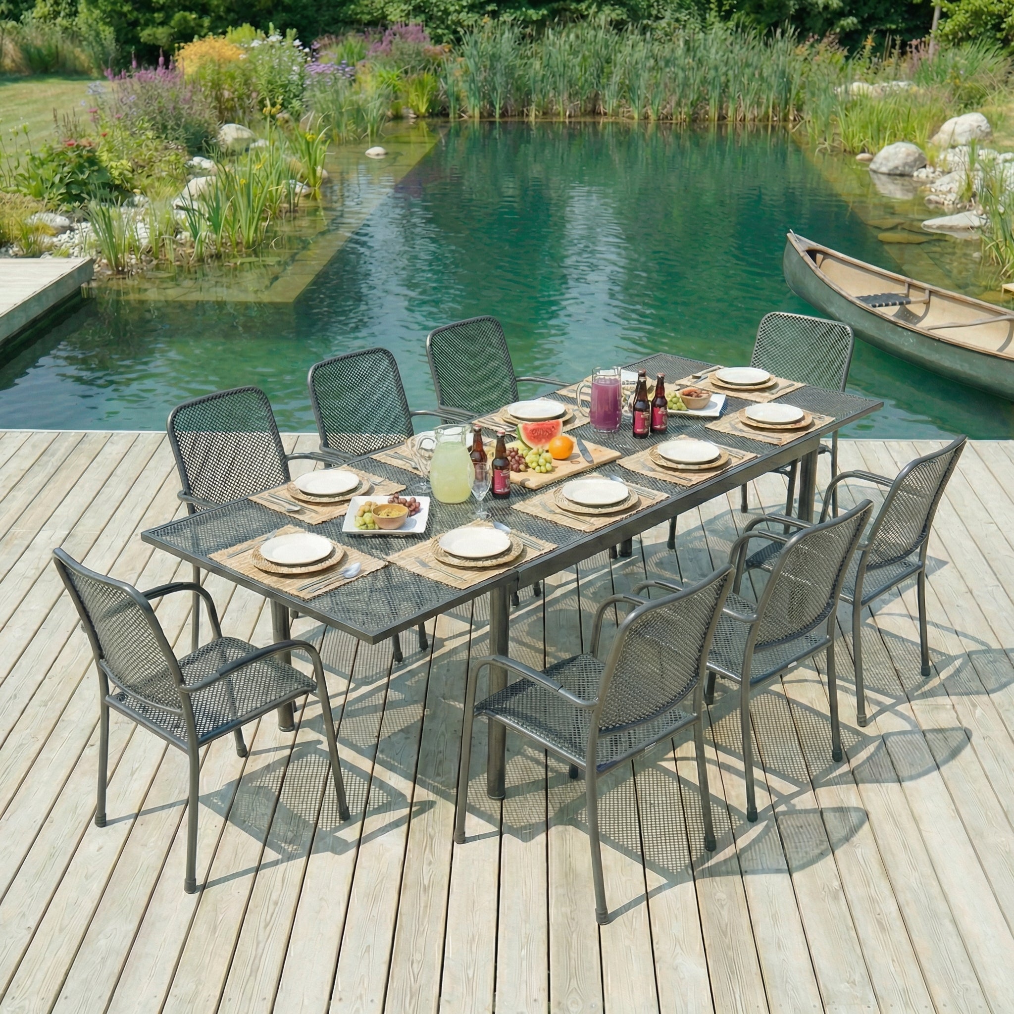 Outdoor dining setup on a wooden deck by a pond with chairs and a table.
