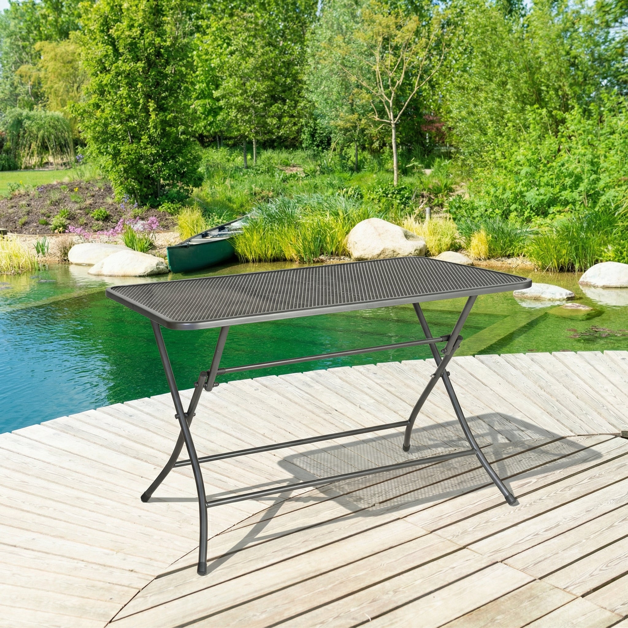 Black metal table on a wooden deck by a pool with greenery in the background