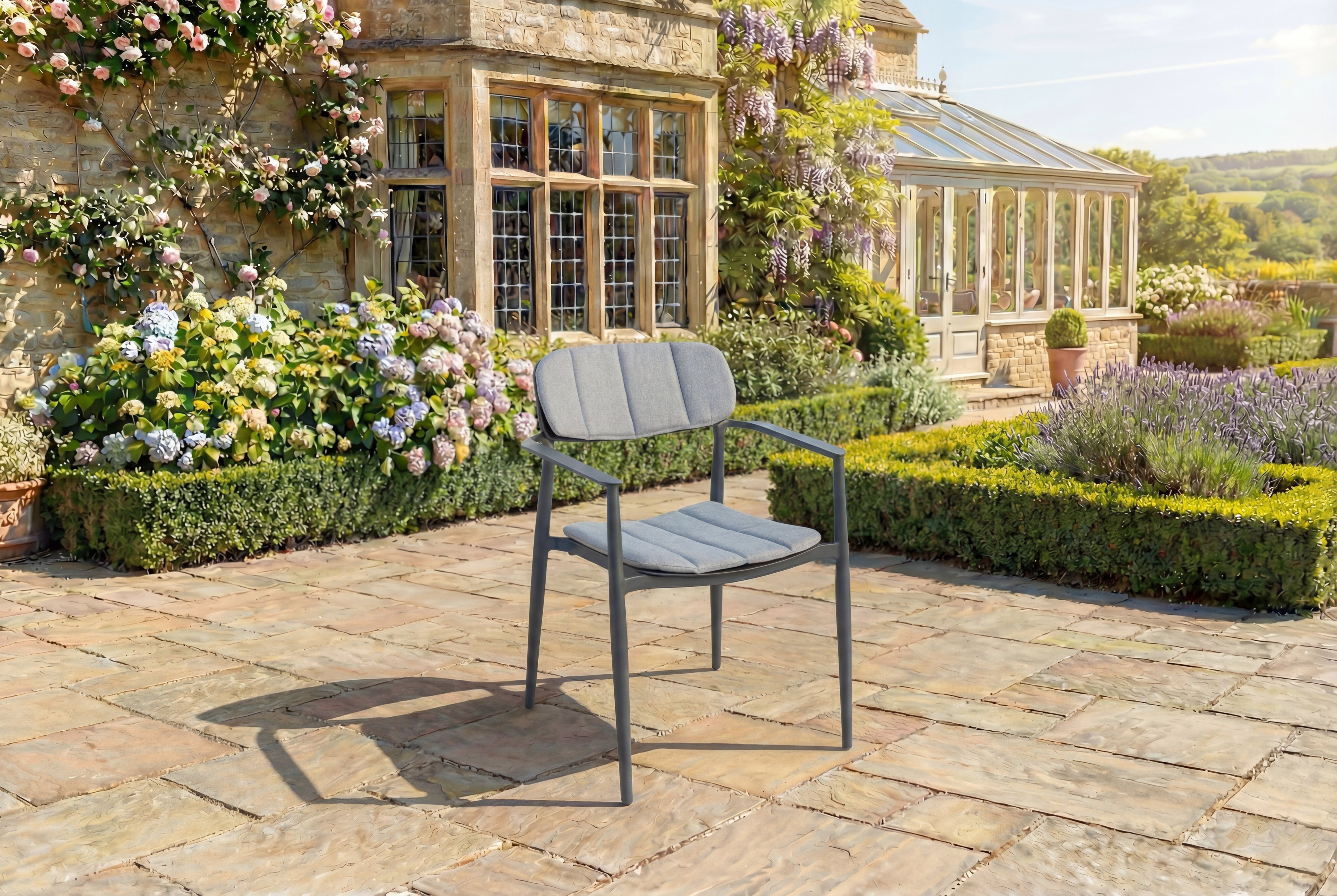 Grey outdoor armchair on a stone patio with a garden and house in the background