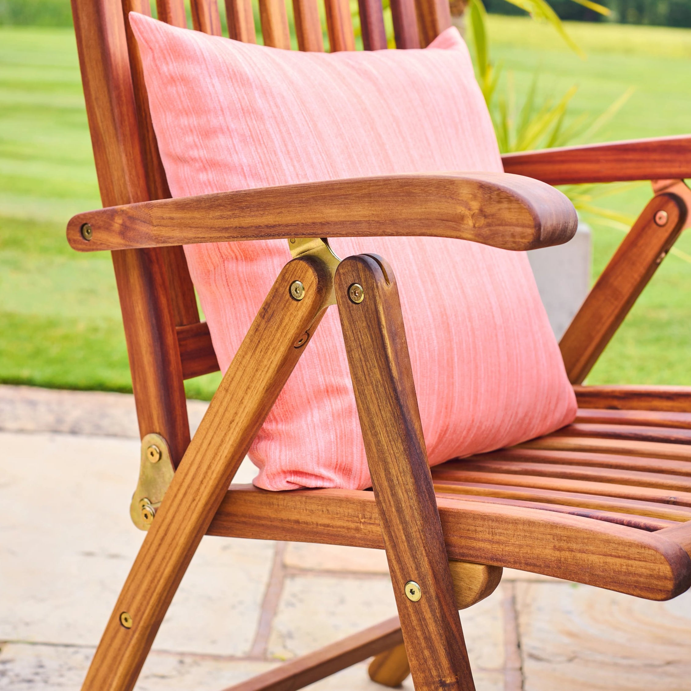 Wooden chair with a pink cushion on a blurred outdoor background