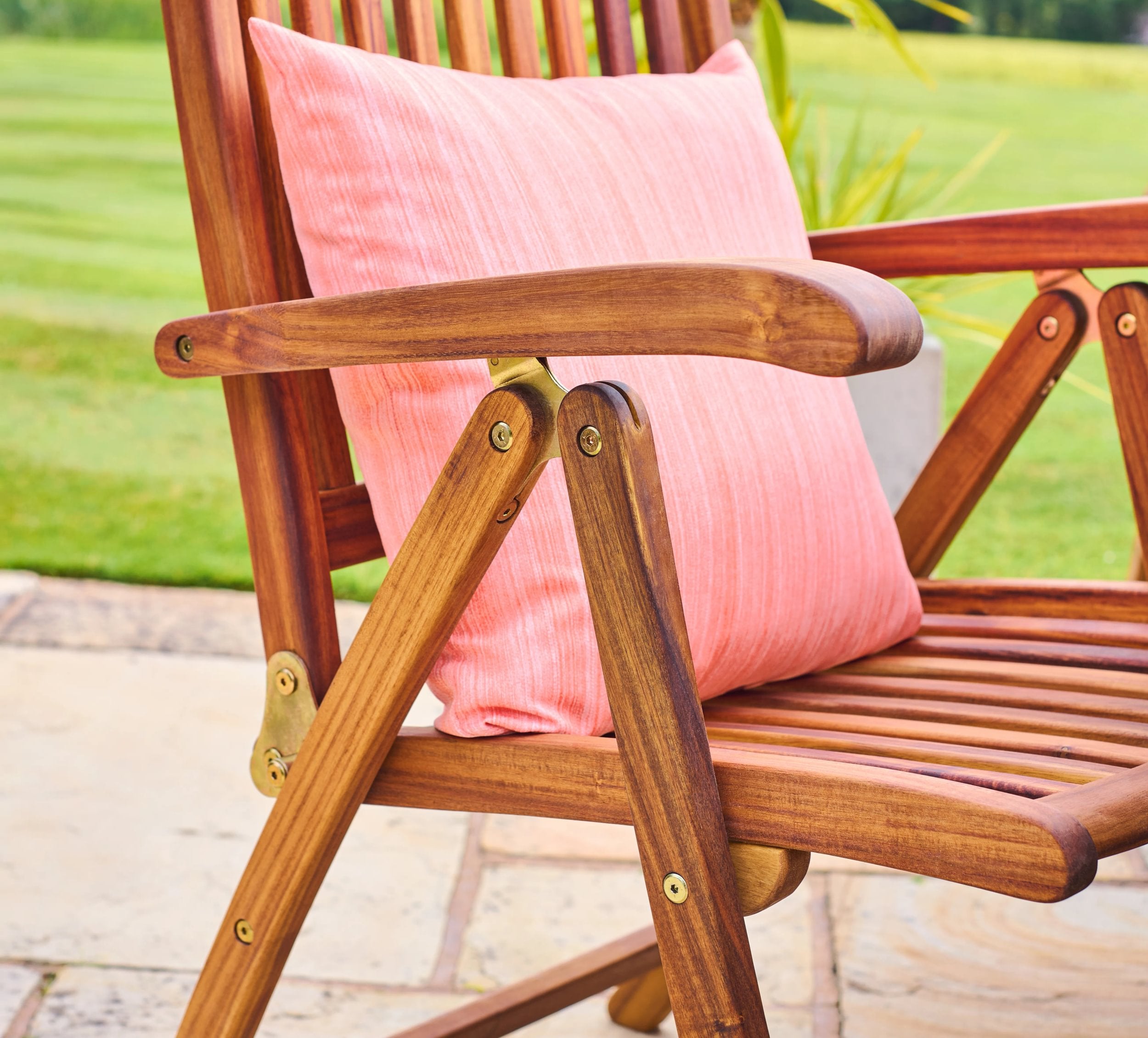 Wooden chair with a pink cushion on a blurred outdoor background