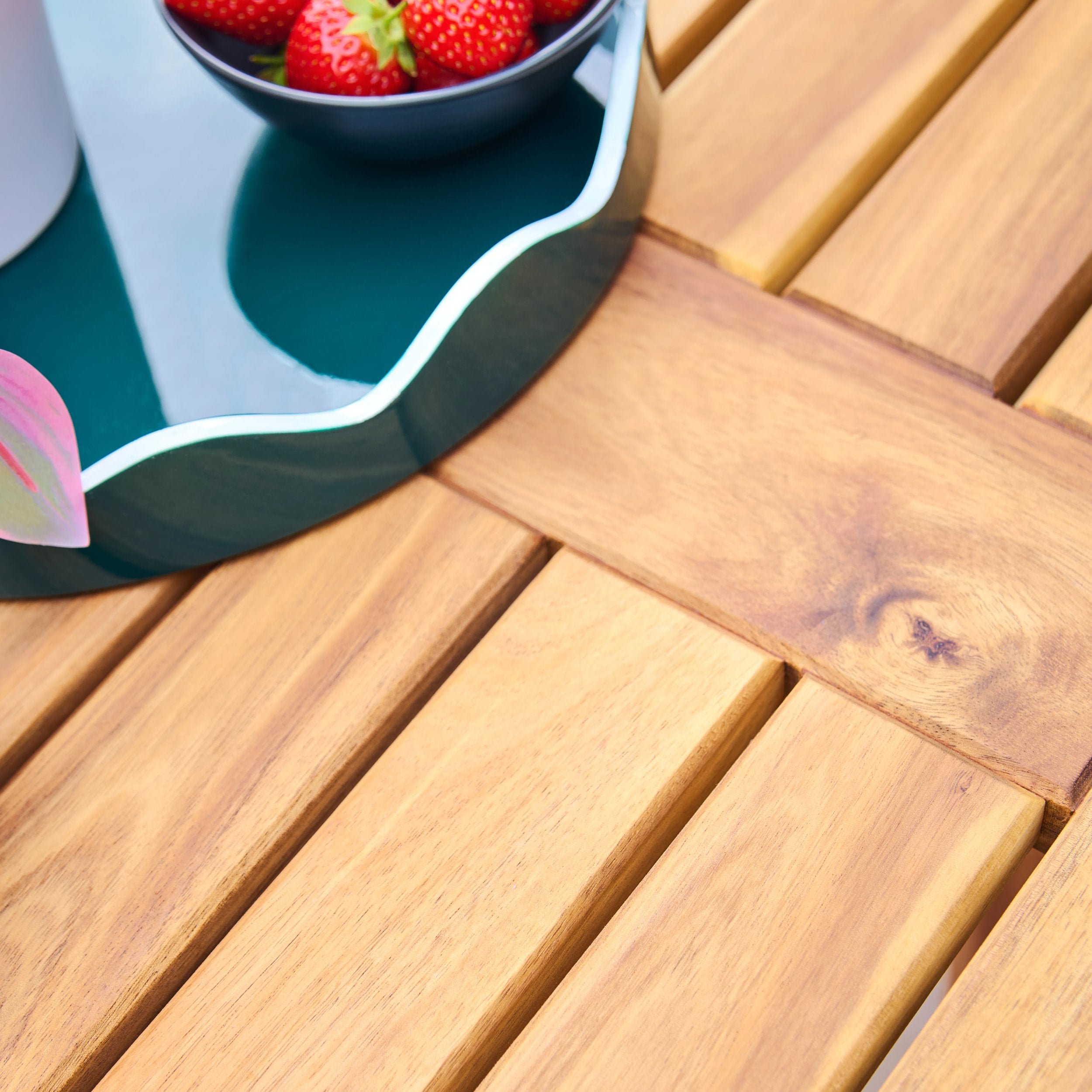 Wooden table with a bowl of strawberries on a blue coaster