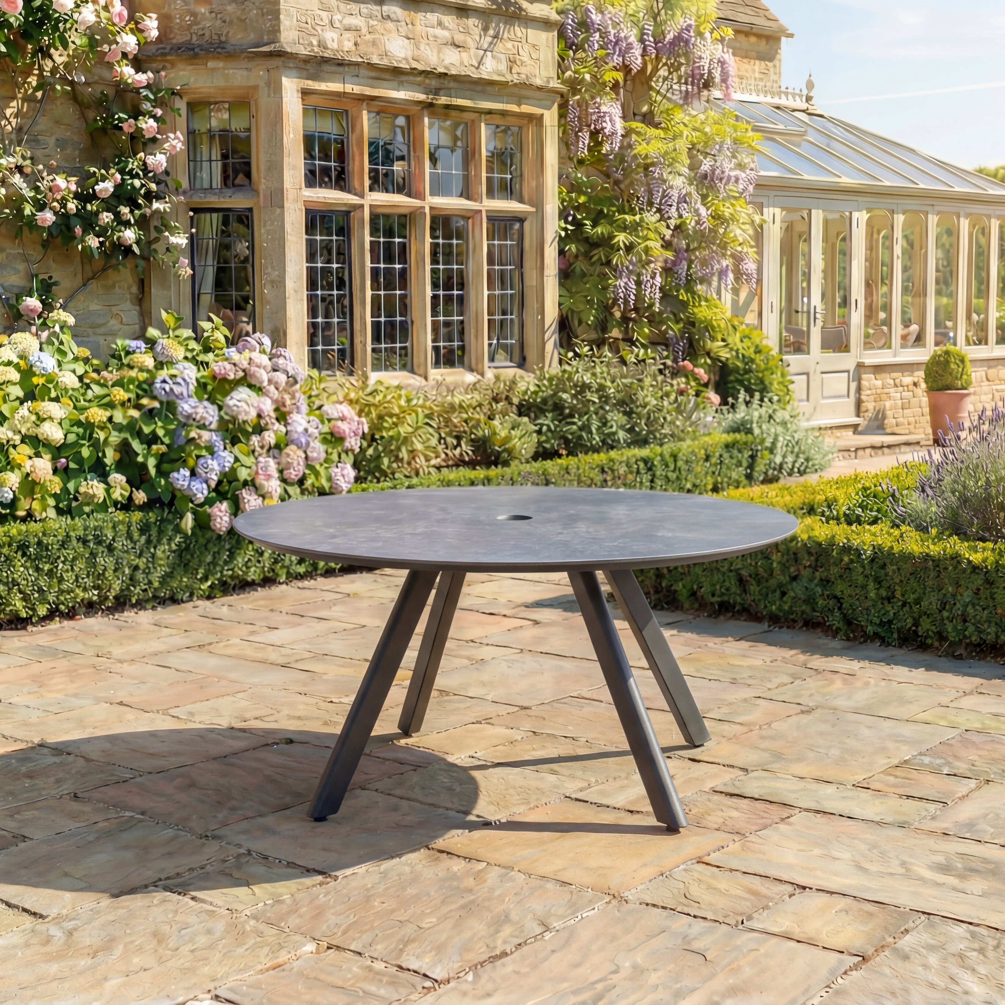 Round outdoor table on a stone patio with floral and garden background