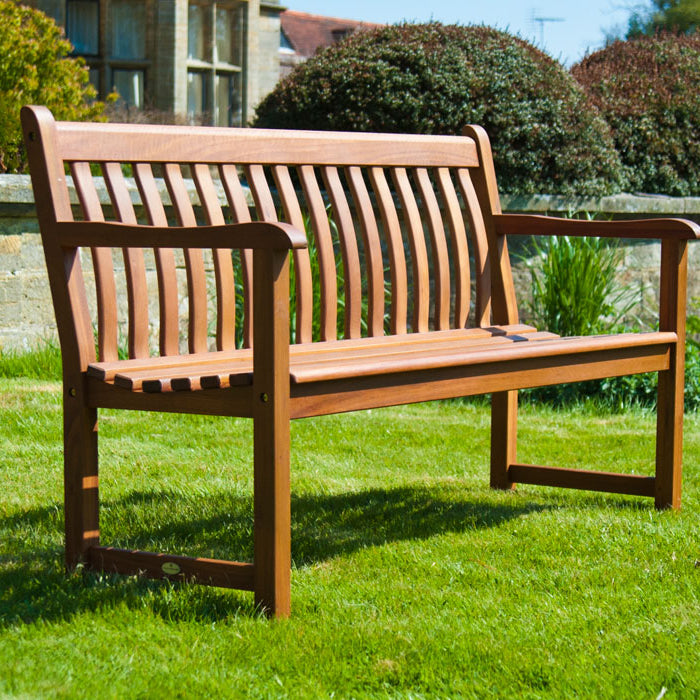 Cornis Broadfield Wooden bench 5ft in a garden setting with green grass and trees.