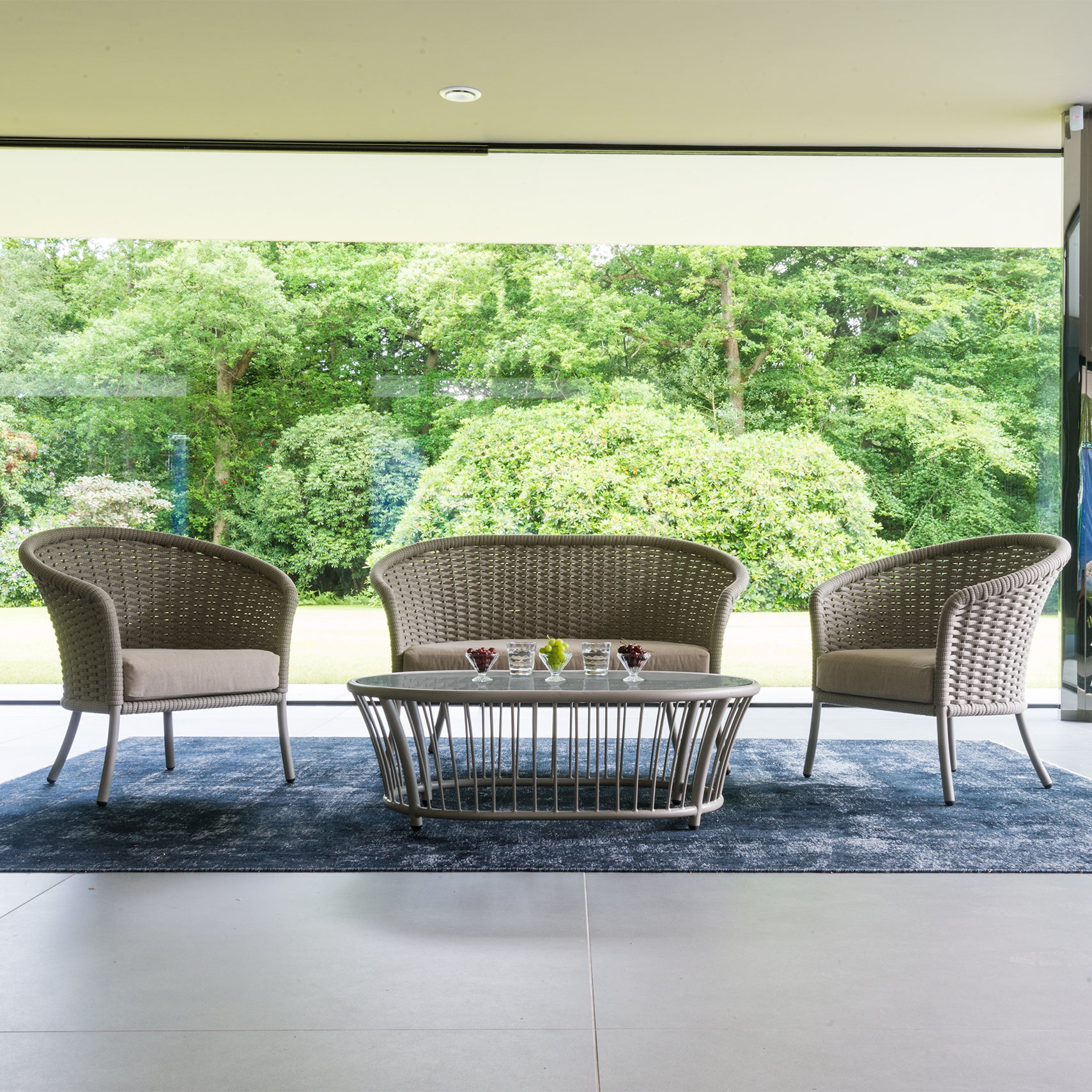 Stylish curved sofa set with two chairs in cream with coffee table set in a large garden room overlooking lawns and trees