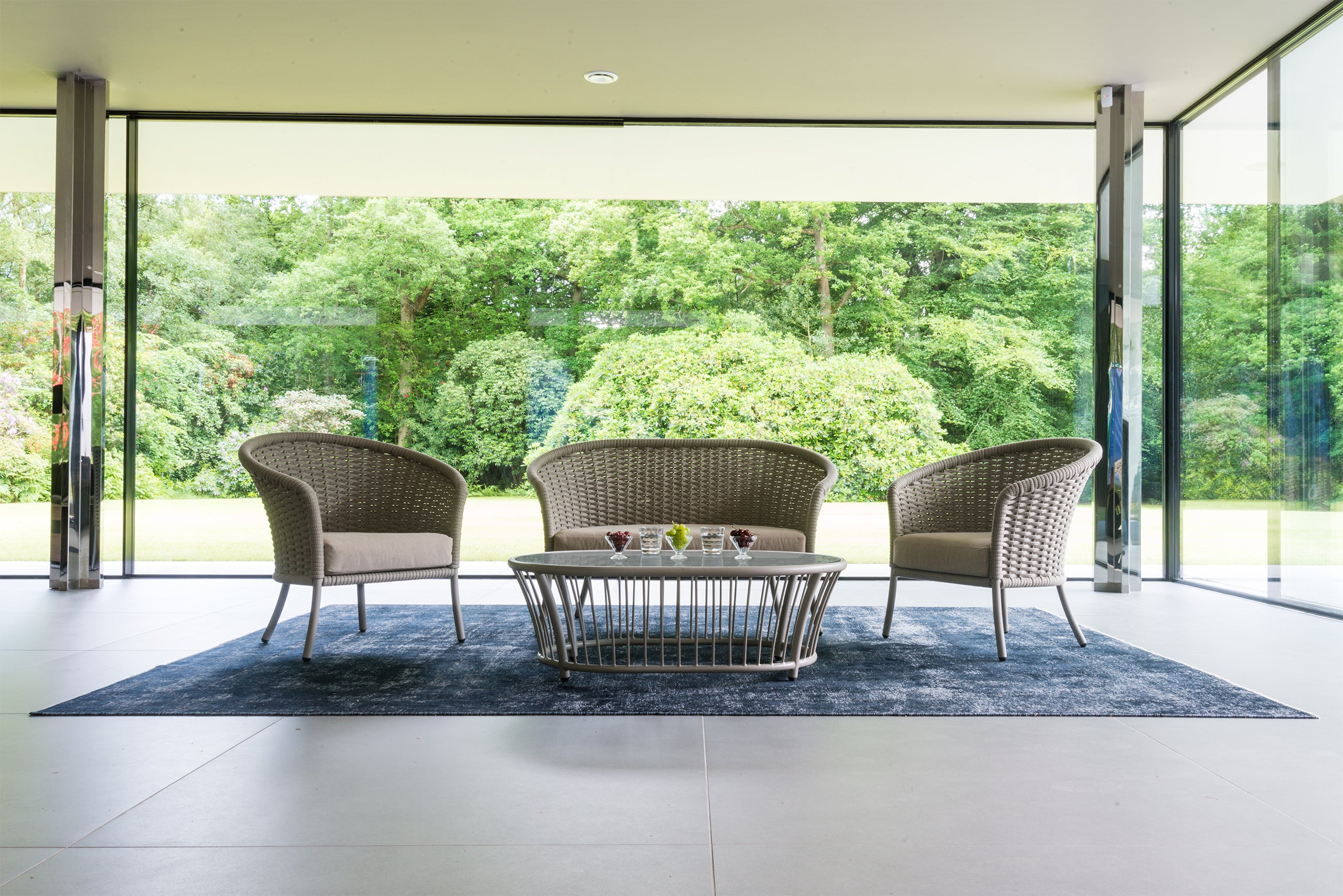 Stylish curved sofa set with two chairs in cream with coffee table set in a large garden room overlooking lawns and trees