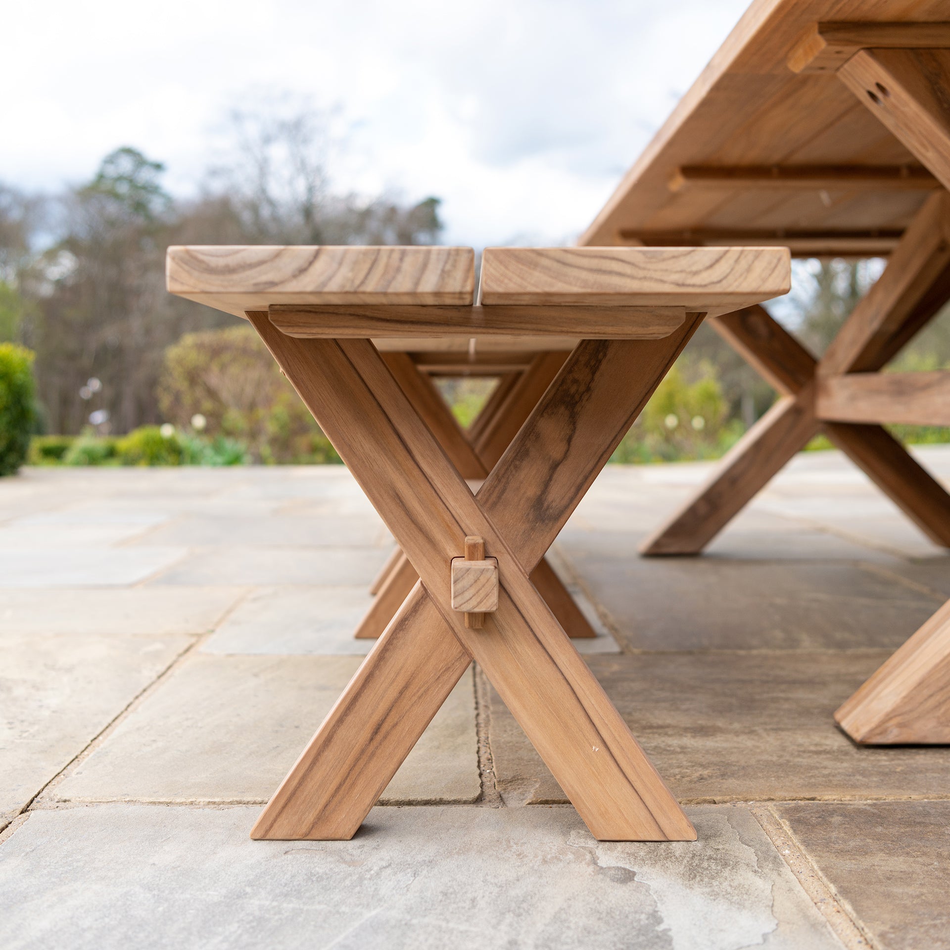 teak plank bench below table on a stone patio
