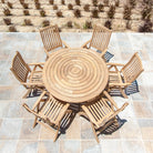 Wooden outdoor dining set with a round table and six chairs on a tiled patio.