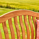 Close-up of a wooden bench seat with a blurred green field background