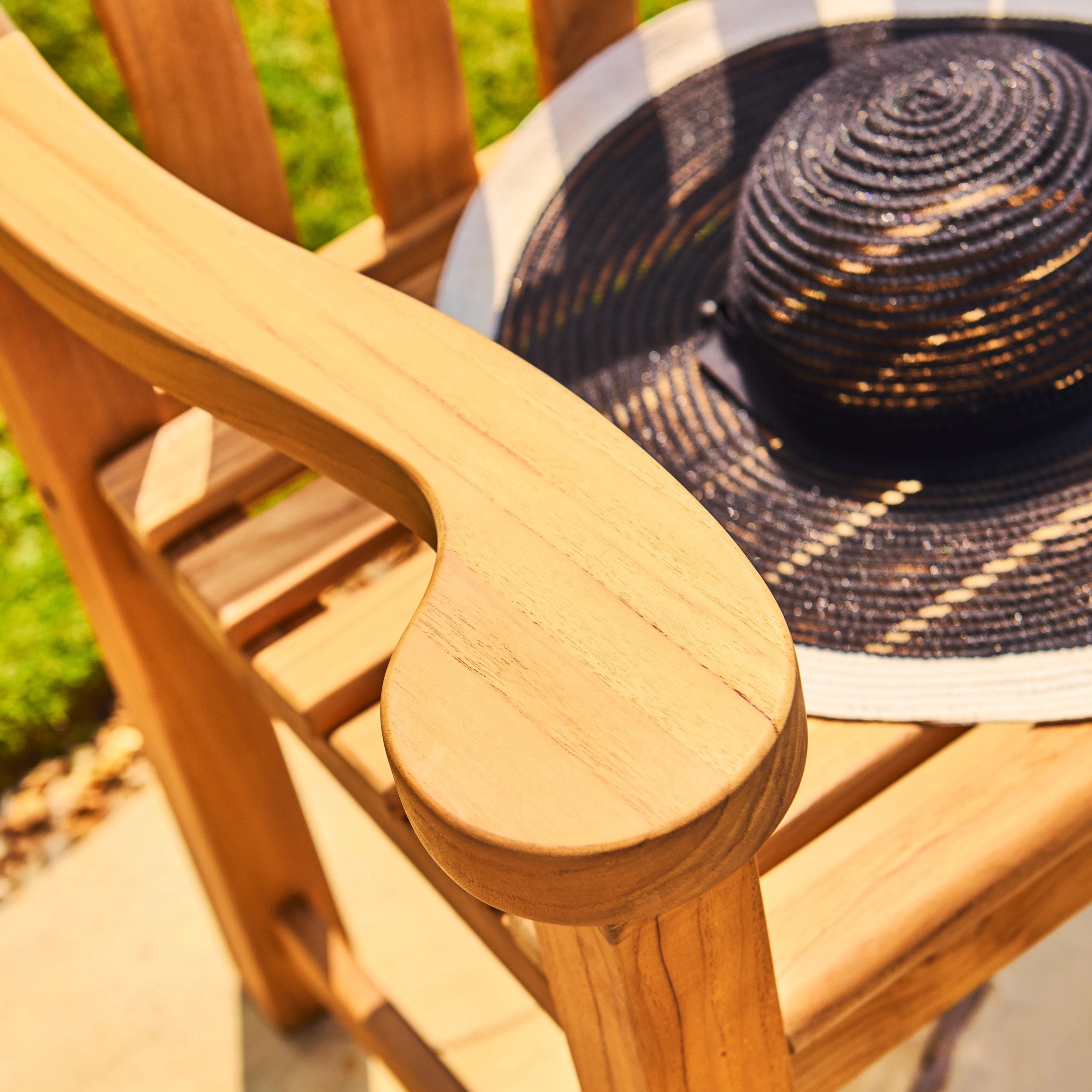 Black straw hat on a wooden chair with blurred greenery in the background