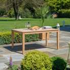 rectangular dining table on a patio with food and drink with a lawned background