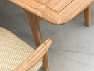 Close-up of a wooden chair with a woven seat on a neutral background