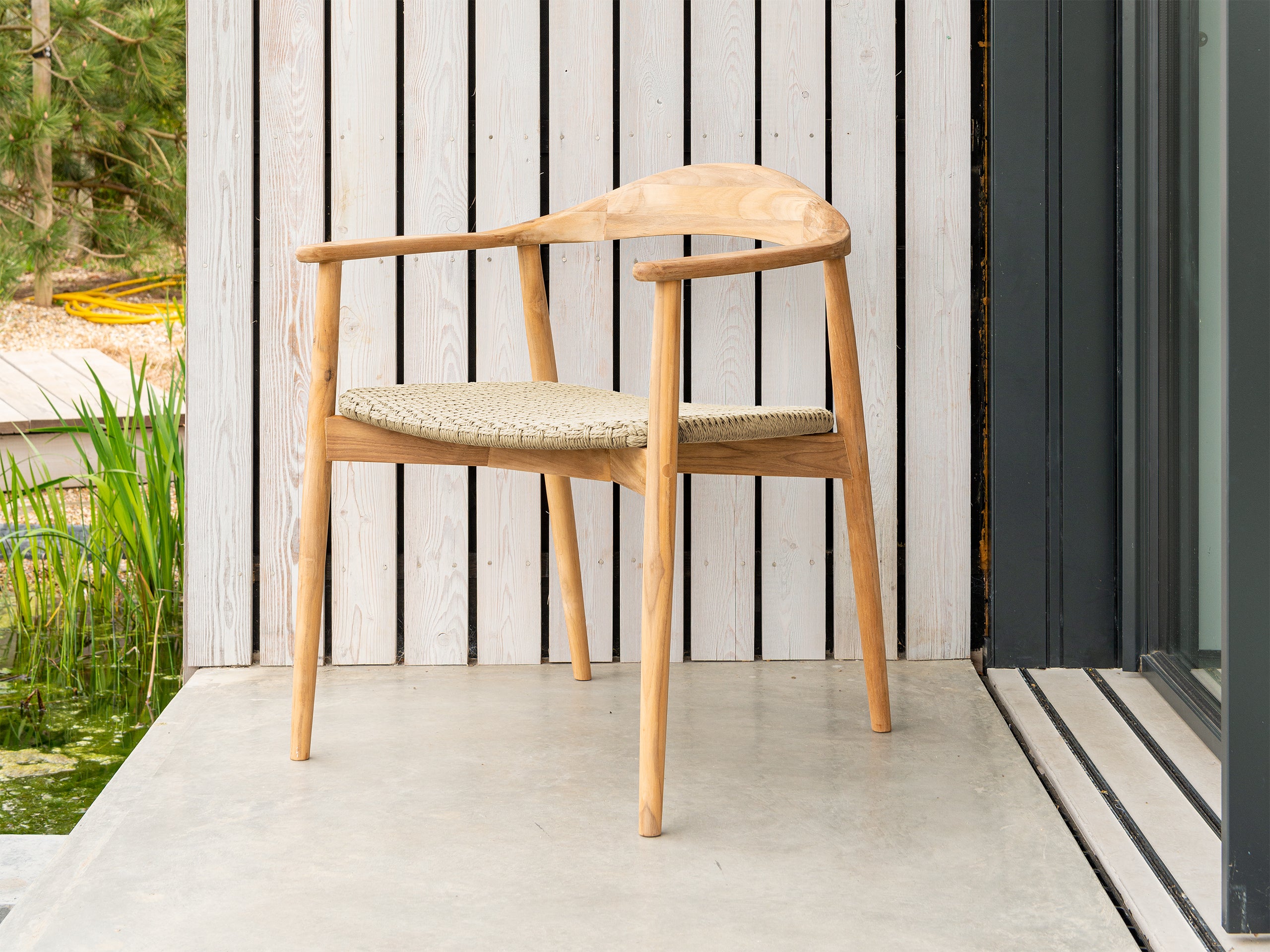 Curved outdoor armchair beautifully styled with woven seat pad