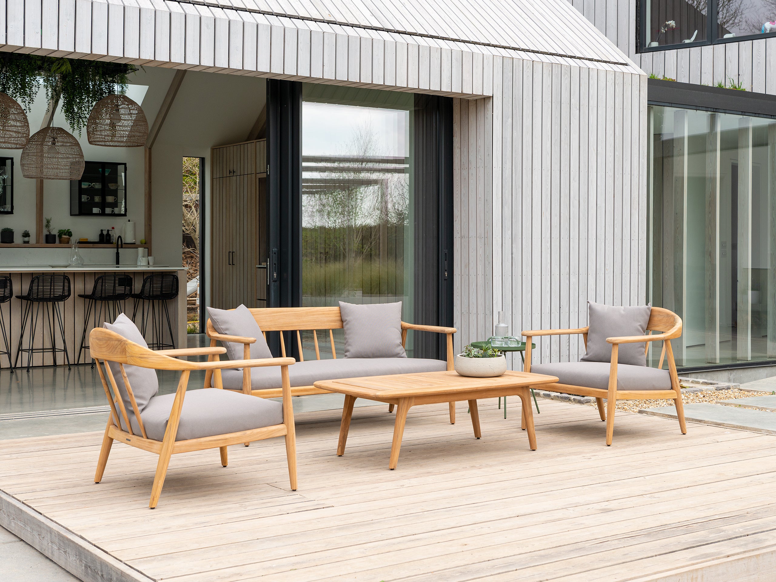 Danish style low lounge set with 2 seater sofa and two curved armchairs with coffee table on a deck