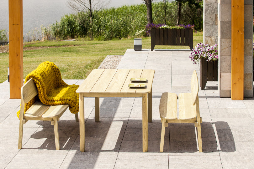 Outdoor pine patio set with wooden table and stylish bench chairs on a tiled patio.