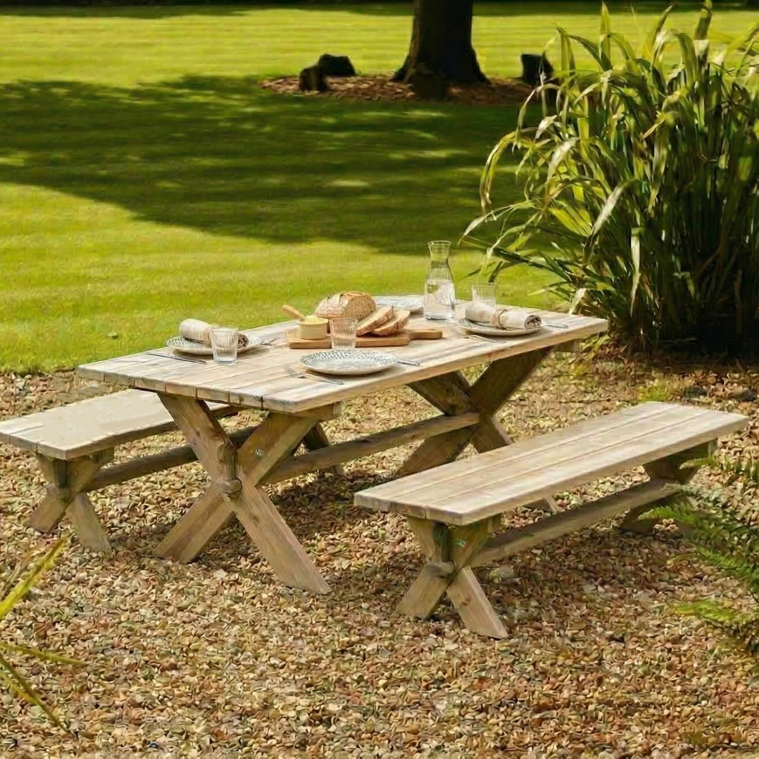 Wooden picnic table with food and drinks set up in a garden
