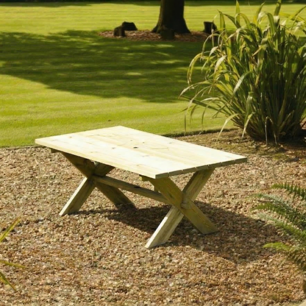 Wooden garden table on a gravel area with grass and plants in the background