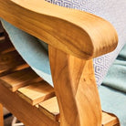 Close-up of a wooden chair with a light blue blanket and patterned cushion