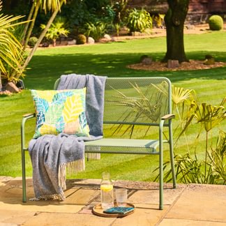 Chair with colorful cushions and a bottle on a patio with a garden view