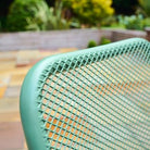 Close-up of a green metal chair with a blurred outdoor background