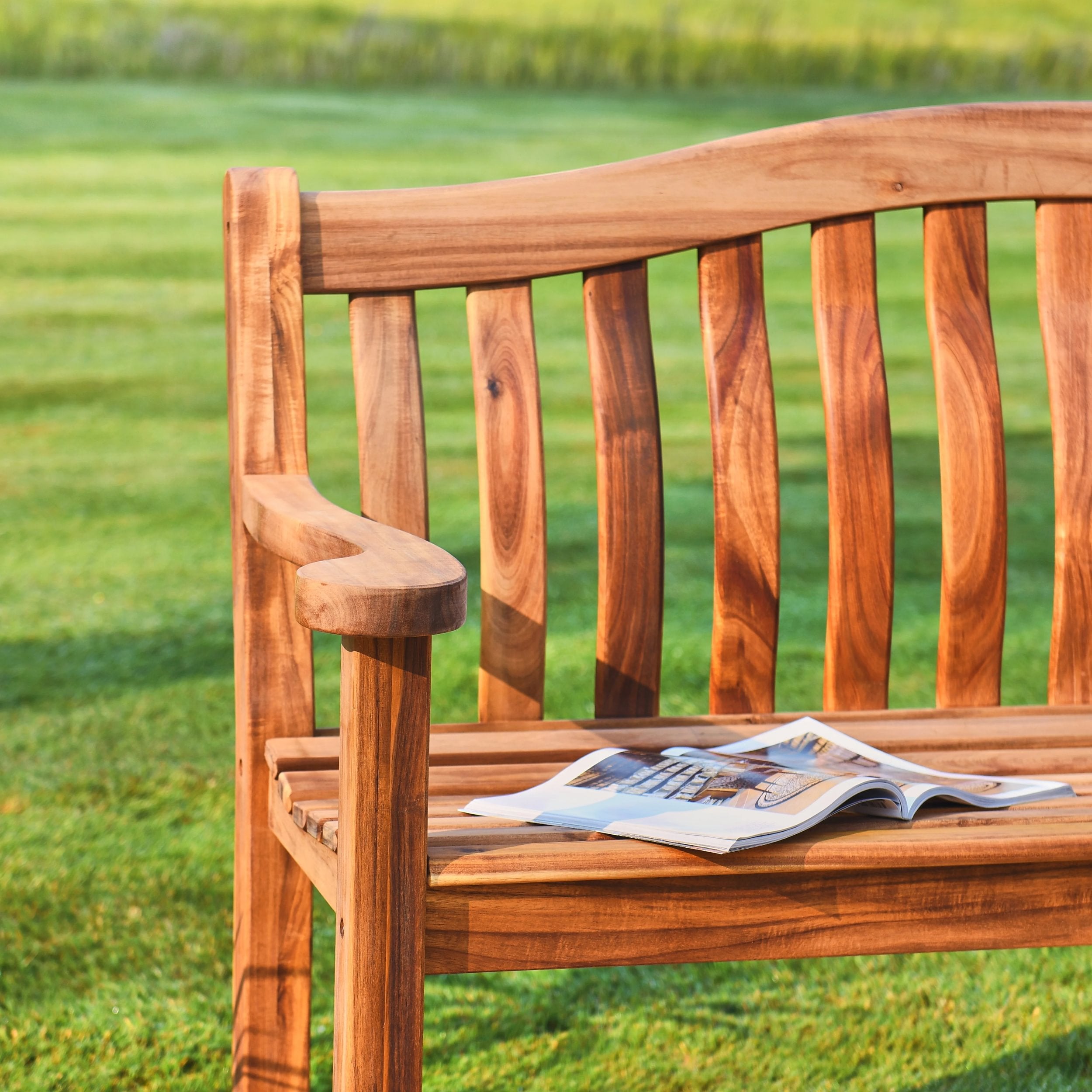 Wooden bench with a magazine on it, set against a grassy background