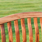 Wooden bench seat with a blurred green grass background