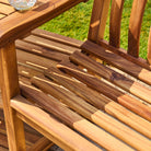 Close-up of a wooden chair with a blurred green outdoor background