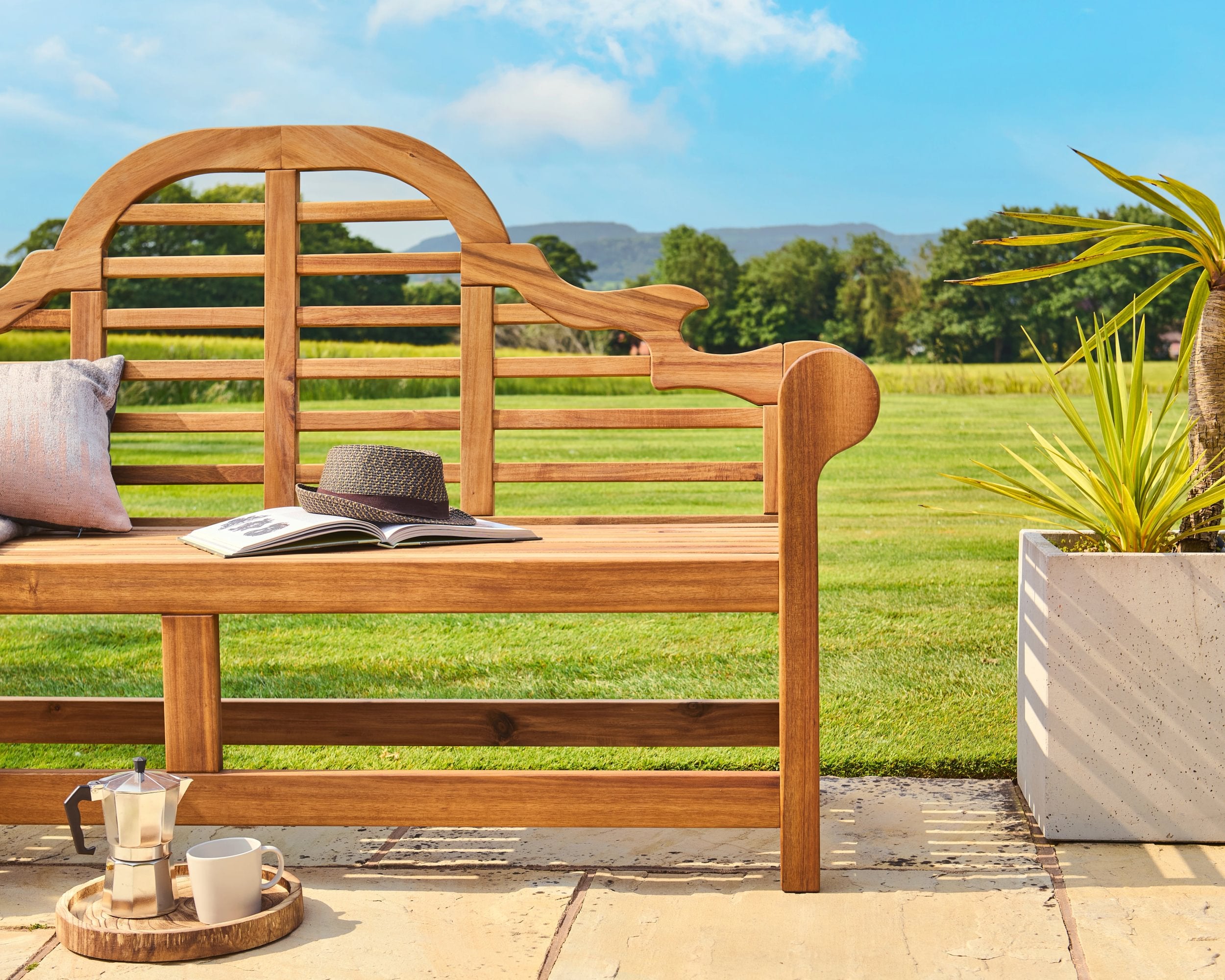 Wooden bench with a hat, book, and small tray in a garden setting