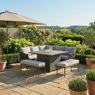 Outdoor patio set with table, chairs, and umbrellas on a stone patio with garden view.