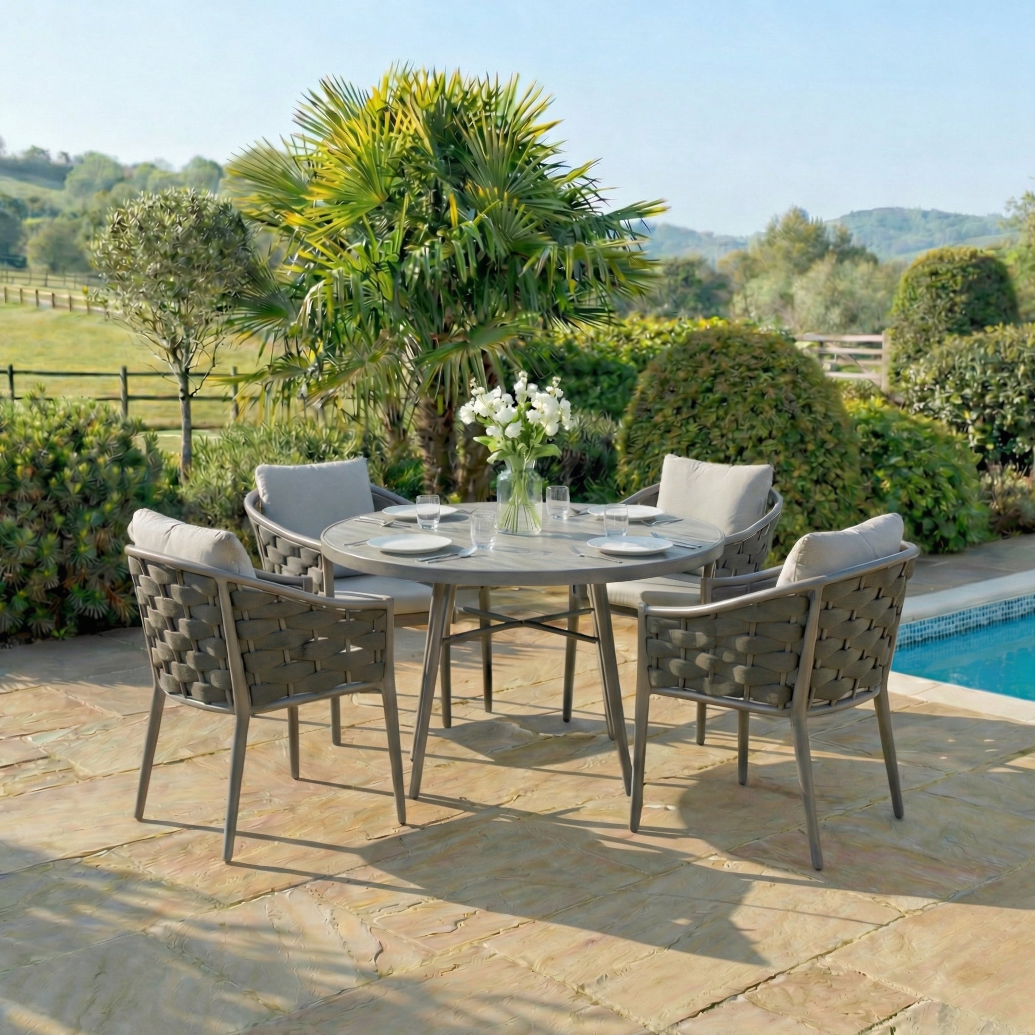 Outdoor patio set with round table and chairs near a pool