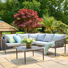 Outdoor patio set made by Alexander Rose with a sofa, coffee table, and decorative elements on a stone patio.