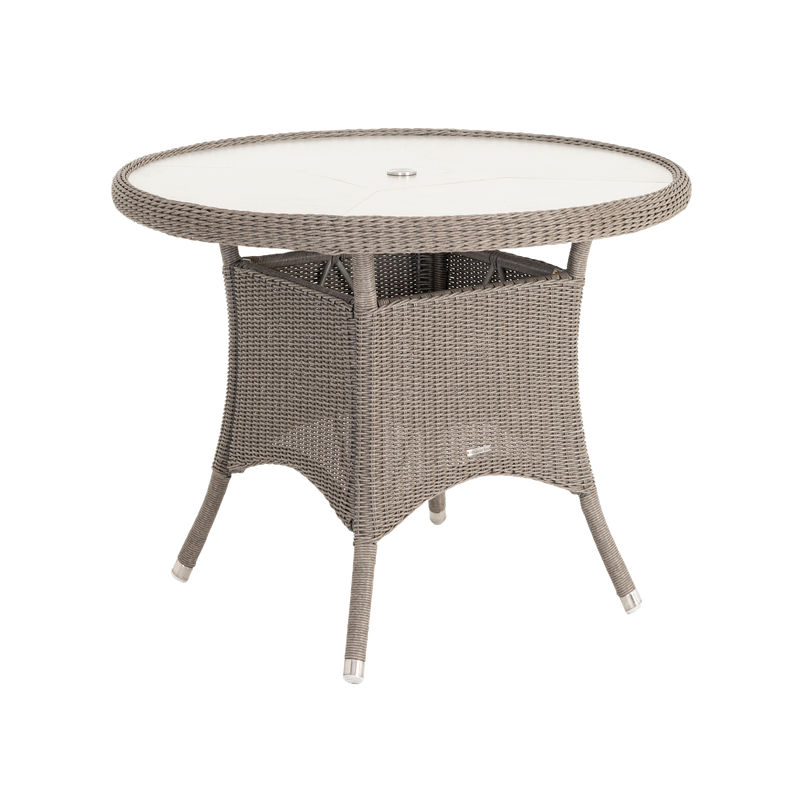 Round outdoor table with wicker frame and glass top on a white background