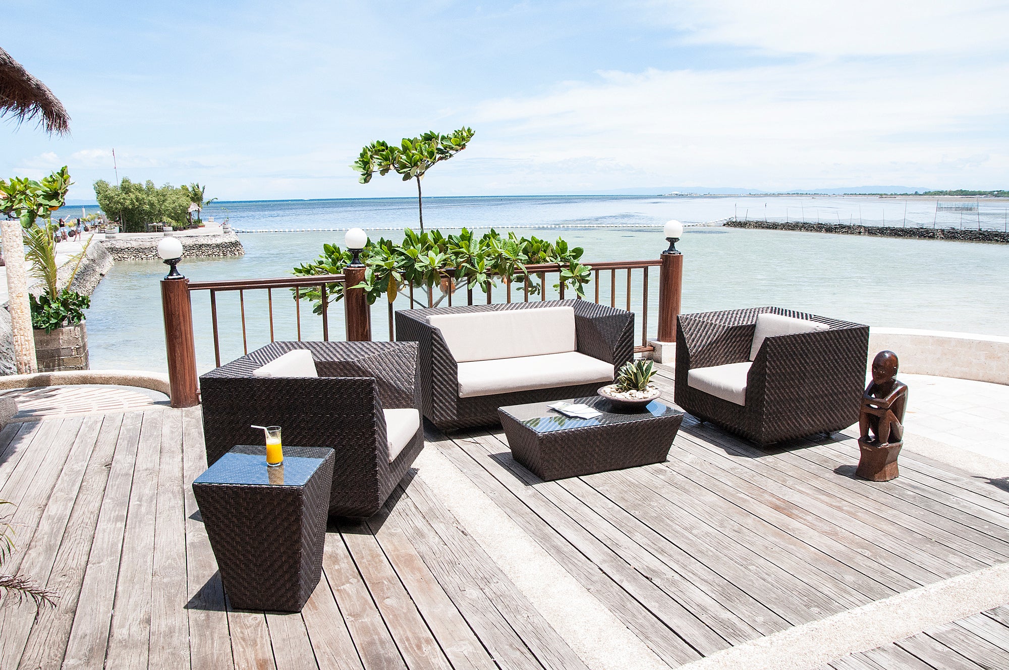 Outdoor furniture set on a wooden deck with a scenic view of water and sky.
