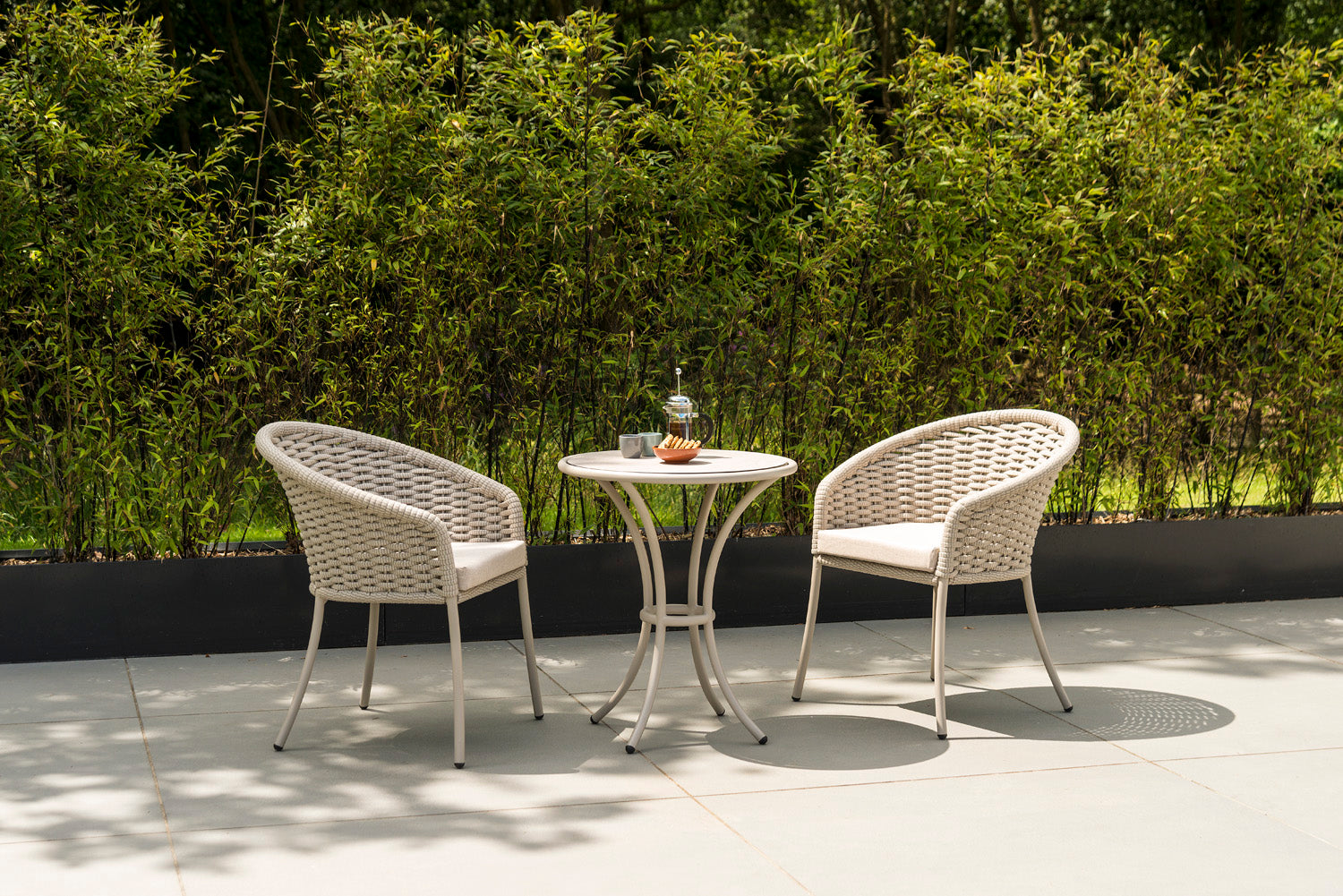 Beige rope-woven outdoor chair set with a small table on a patio.