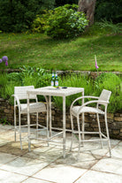Two ultra modern rattan bar stools with curved arms and a bar table on a patio