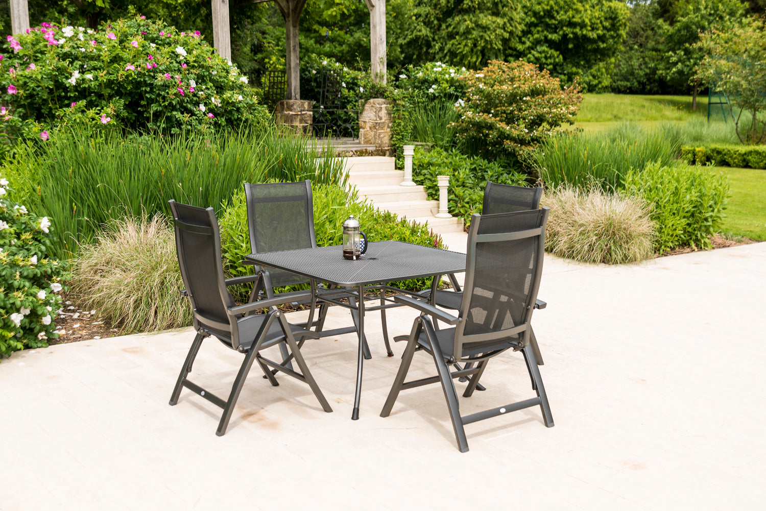 Outdoor patio set with table and chairs in a garden setting