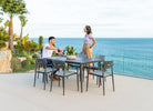 Two people sitting at a dining table with a scenic ocean view.
