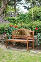 Wooden bench in a garden setting with flowers and stone wall