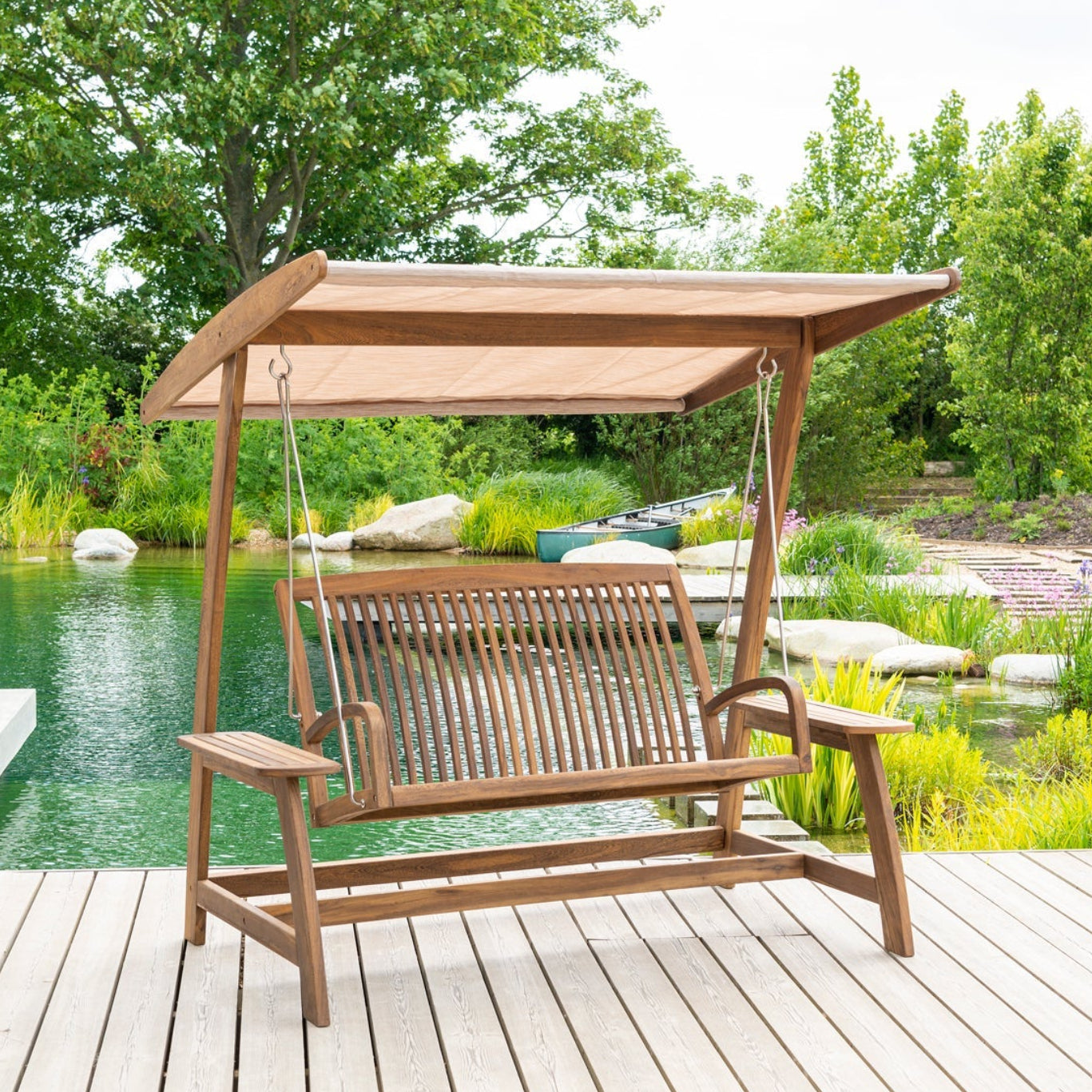 Wooden swing chair with canopy on a wooden deck by a poolside.