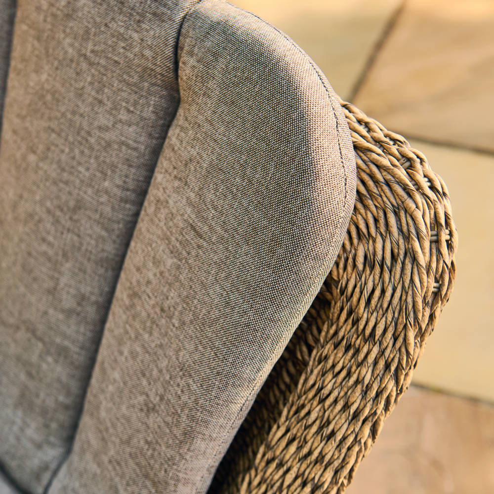Close-up of a grey cushion with wicker armrest on a chair.