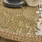 Wicker table with glass top and decorative items including plates and glasses.